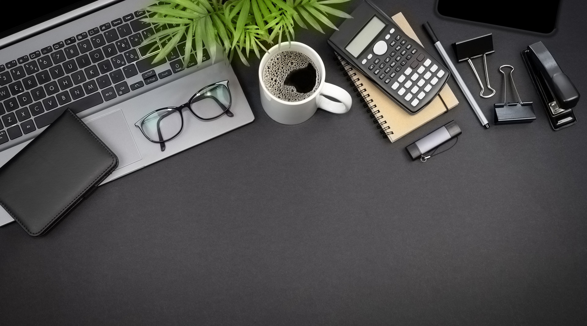 Top view of laptop, glasses and stationery. Freelance workspace concept with copy space